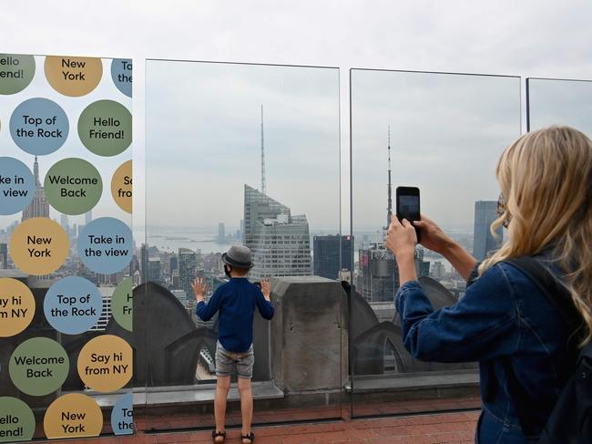 A woman and her son take pictures during the reopening of the Top of The Rock observation deck on August 6, 2020 in New York City. - The Top of the Rock was forced to temporarily close in March to help limit the spread of COVID-19. However, the Observation Deck at Rockefeller Center has the benefit of being one of the largest in New York City, with more than 9,500 square feet (883 square meters) of outdoor deck space. (Photo by Angela Weiss / AFP)