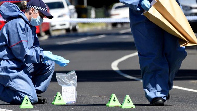 Forensic police pick up spent shells from the road. Picture: Nicole Garmston