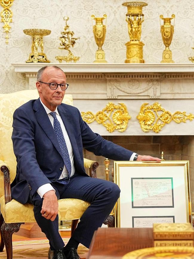 German Chancellor Friedrich Merz gives US President Donald Trump a present of a facsimile of the birth certificate of his grandfather, Friedrich Trump, gin the Oval Office.