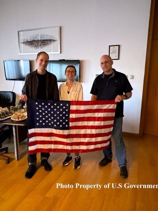 Evan Gershkovich, Radio Free Europe journalist Alsu Kurmasheva, and former US Marine Paul Whelan pose with an American flag in the airport lounge in Ankara, Turkey, ahead of their flight to the US. Picture: US Government/Getty Images