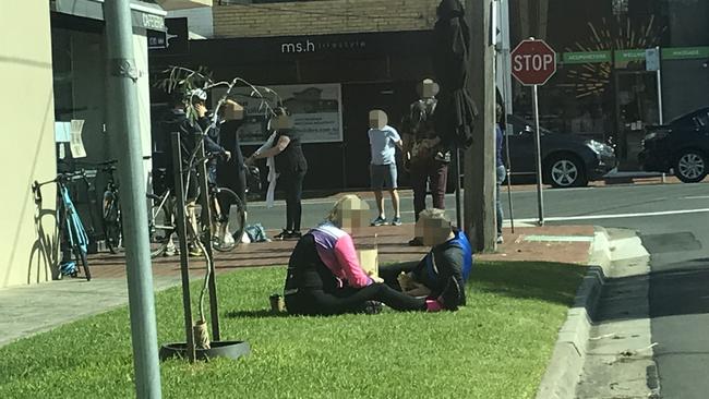 Two people sit on the grass to eat their coffee and food at Black Rock.