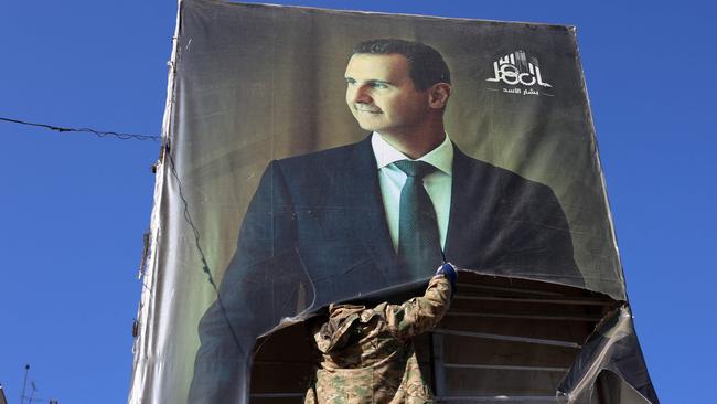 An anti-government fighter tears down a portrait of Syria's President Bashar al-Assad in Aleppo. Picture: AFP