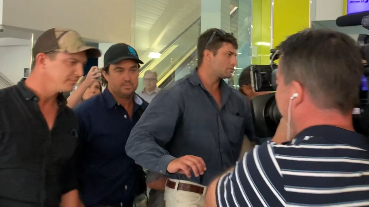 Wright, 43, pictured in the dark cap, arrives at Darwin Airport on November 29 after NT Police issued a warrant for his arrest. Picture: Sierra Haigh