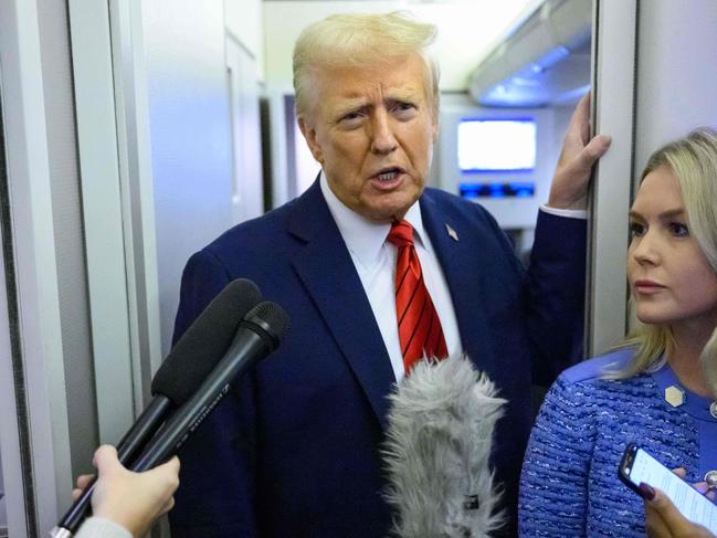 US President Donald Trump, watched by White House Press Secretary Karoline Leavitt, speaks to reporters while in flight on Air Force One en route Joint Base Andrews, on January 27, 2025. (Photo by Mandel NGAN / AFP)