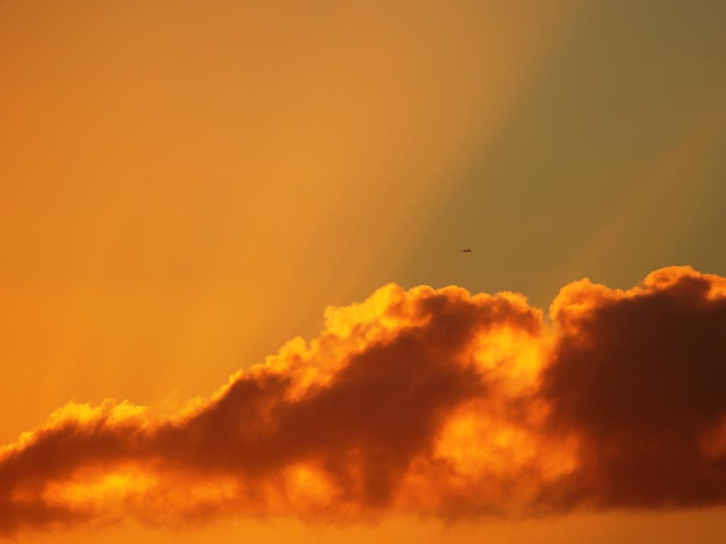 2019 could be the hottest year yet. A plane flies through sun rays at sunrise off Dee Why. Picture: John Grainger