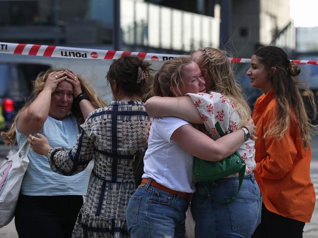 People embrace as police evacuate the Fields shopping centre in Copenhagen, Denmark after a mass shooting. Picture: AFP