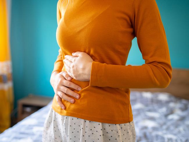 A young woman is having pain in her stomach and holding it with both hands