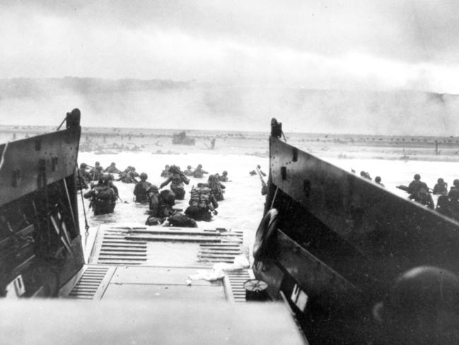 Under heavy German machine gun fire, American infantrymen wade ashore off the ramp of a Coast Guard landing craft during the D-Day invasion. Picture: AP