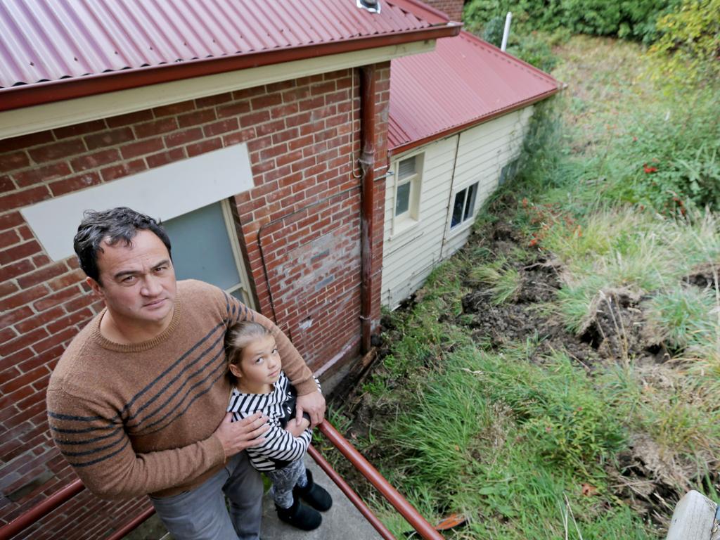 Vick Paice and his daughter Evey, 10, inspect the damage after a landslide in the backyard of their Sandy Bay home left piles of dirt, rocks, mud and plants piled against the back of the house. Picture: PATRICK GEE