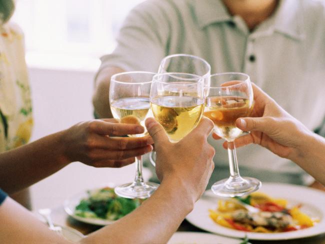 Hands toasting wine glasses at dinner party. Generic image.