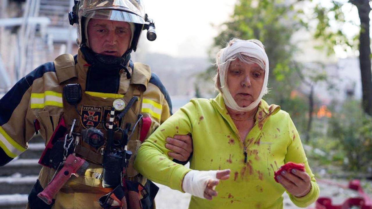 An injured woman is helped to safety after blasts rocked Kyiv. (Photo by HANDOUT / State Emergency Service of Ukraine / AFP)