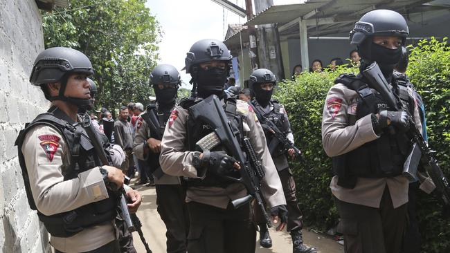 Police officers stand guard at a residential neighbourhood where police conducted a raid on a house where three suspected suicide bombers were killed, in Tangerang, Indonesia Wednesday on December 21. Picture: AP / Tatan Syuflana