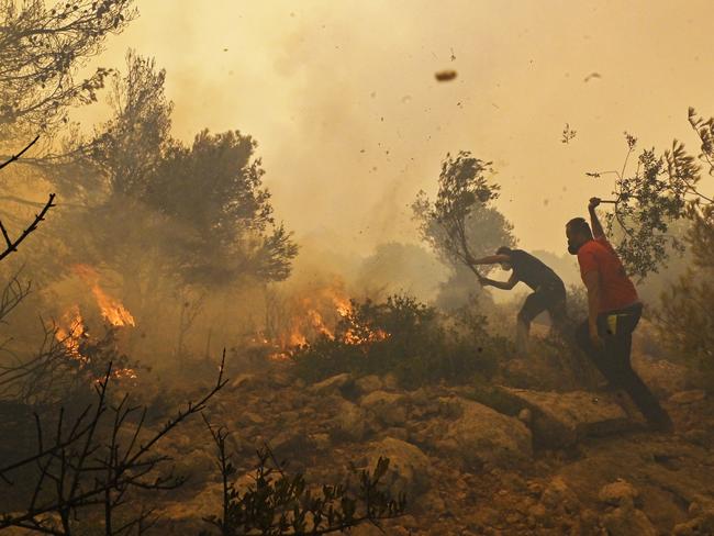 Locals help firefighters battle a wildfire near the village of Vlyhada near Athens as the Greek capital endures a relentless heatwave. Picture: Milos Bicanski / Getty Images