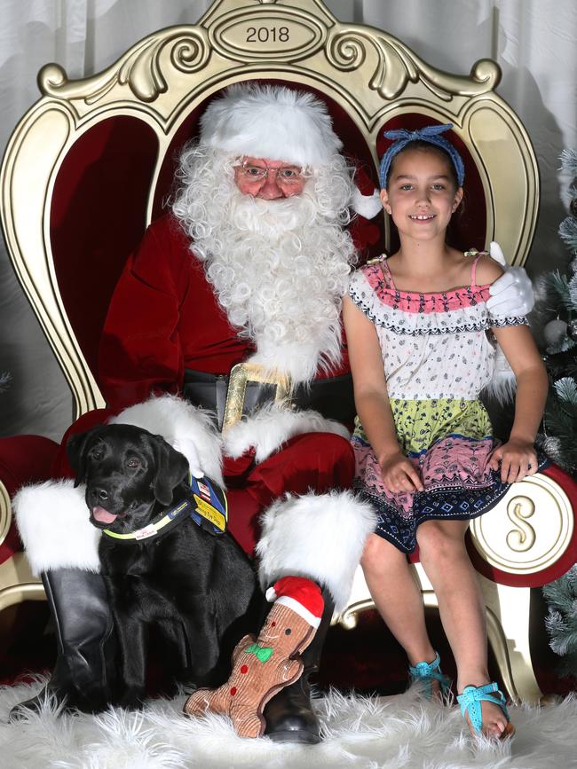 Santa gets a photo at Eastland with Bailey, 9, and Trilby the seeing eye dog. Picture: Stuart Milligan