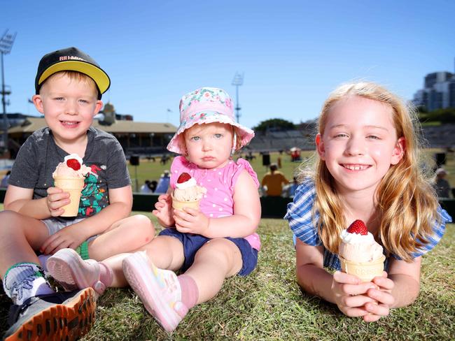 Caleb Schipper 4 yrs, Lara Schipper 18 months and Kate Schipper 7 yrs from Bellbird Park, eating Strawberry Sundaes' on the hill, Ekka 2023. Photo: Steve Pohlner