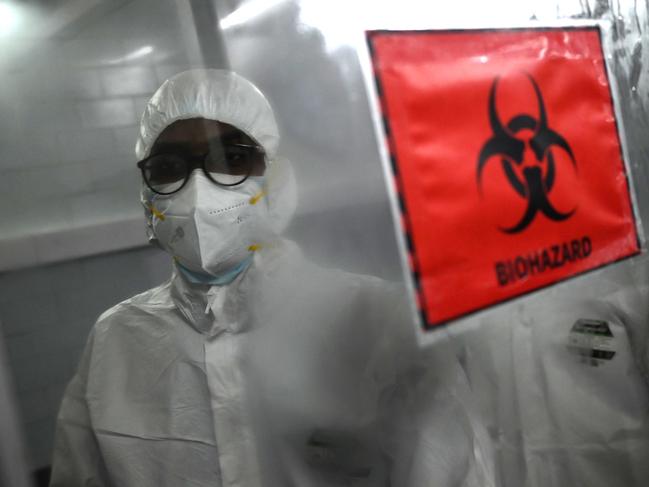 Technicians wearing personal protective equipment (PPE) suits stand behind a biohazard sign inside a molecular laboratory facility set up to test for the monkeypox disease in Chennai. Picture: AFP