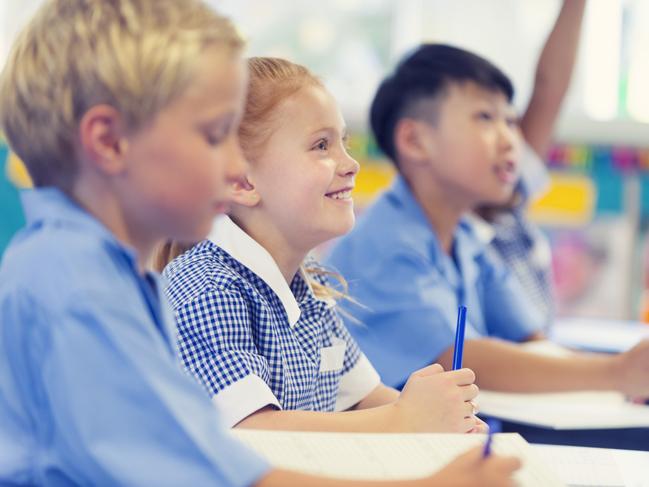 Group of children listening to the teacher. They are in a classroom. Multiethnic group with Caucasian and Asian kids. School girl is smiling and happy