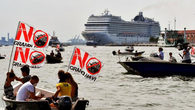 Environmental protesters from the "No Grandi Navi" group, demonstrate aboard small boats against the presence of cruise ships in the lagoon, as the MSC Orchestra cruise ship (Rear) leaves Venice on June 5. Picture: AFP