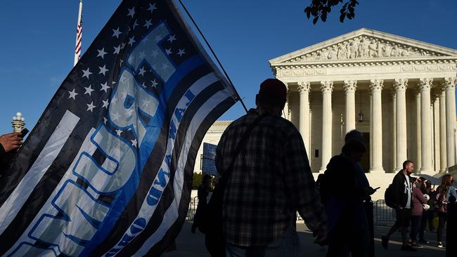 A Trump supporter waves a thin blue line flag in support of all law enforcement officers, outside the US Supreme Court ahead of Ms Amy Coney Barrett’s confirmation. Picture: AFP.