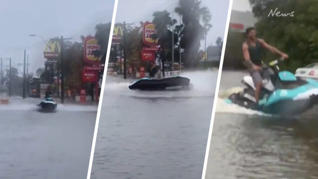 Man rides jet ski past McDonald's in floodwaters