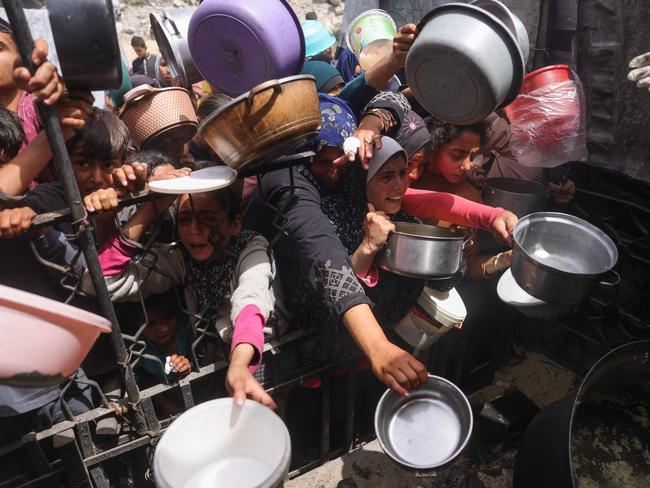 Palestinians try to get a portion of cooked food from a charity kitchen in Jabalia in the northern Gaza Strip last week. Picture: AFP