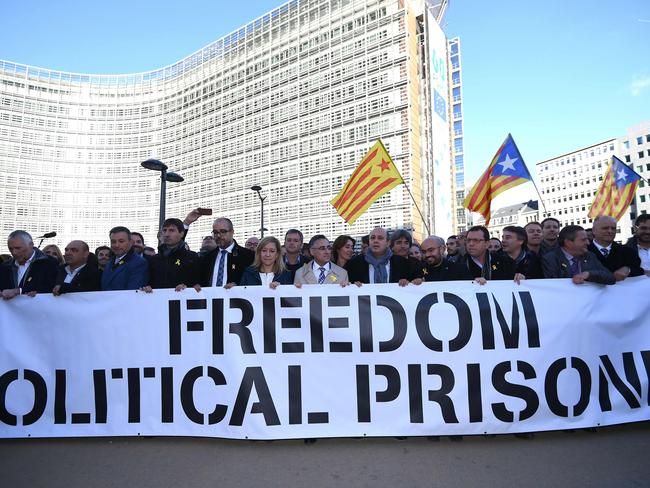 Catalan pro-independence mayors hold a banner as they demonstrate to show solidarity with detained officials in Spain on November 7, 2017 in front of the European Commission building in Brussels.  The sacked leader of Catalonia claimed on November 7 that he fled to Belgium because Spain was preparing a "wave of oppression and violence" against his separatist movement.  / AFP PHOTO / Emmanuel DUNAND