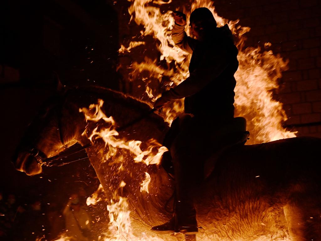 A horseman rides through a bonfire in the village of San Bartolome de Pinares in the province of Avila in central Spain, during the traditional religious festival of "Las Luminarias" in honour of San Antonio Abad (Saint Anthony), patron saint of animals, on January 16, 2022. (Photo by PIERRE-PHILIPPE MARCOU / AFP)