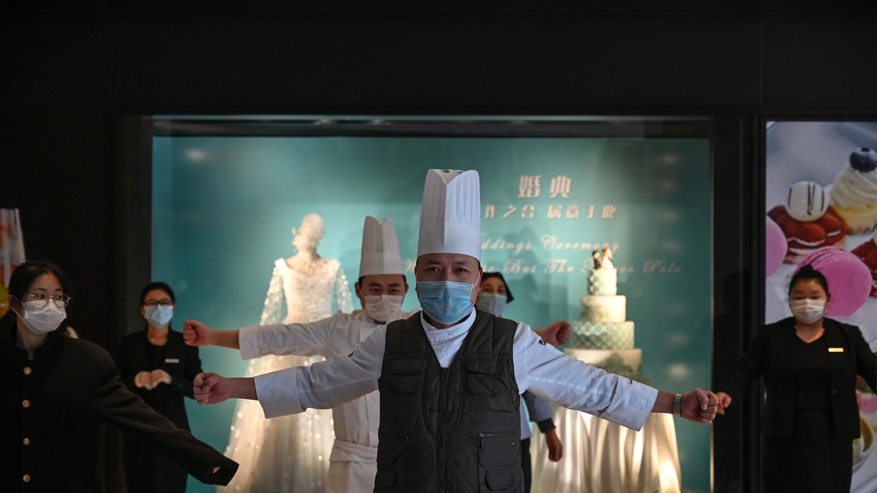 Hotel workers wearing protective masks exercise in the lobby during a staff briefing about how to implement new regulations concerning the current situation in Wuhan. Picture: AFP