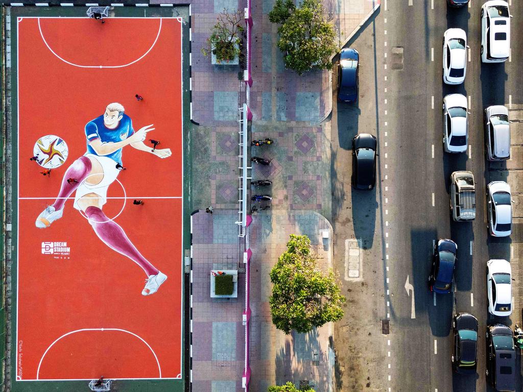 An aerial photo shows boys playing football on a brightly-painted court alongside heavy traffic. Amid Bangkok’s concrete and highways, verdant “pocket parks” are emerging in Thailand’s bustling capital. Picture: Manan Vatsyayana/AFP