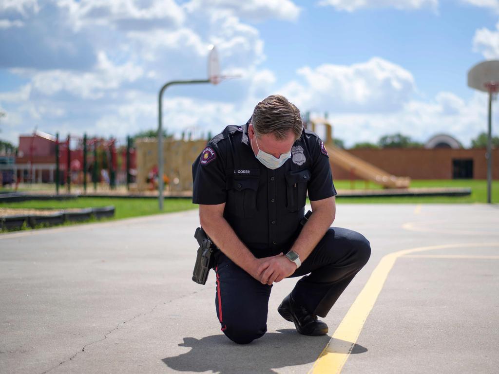 A police officer takes a knee during a 9 minute moment of silence in honour of George Floyd during a "Sit In Protest" at DeepWater Park in Pasadena, Texas. Picture: Mark Felix/AFP