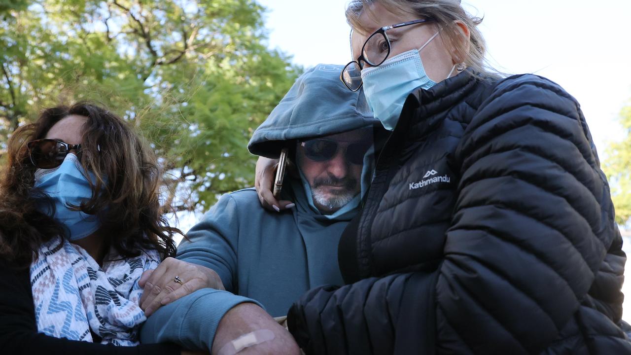 Accused truck driver Ross Phillip Hicks hides outside the Adelaide watch-house, supported by his wife and others, after being charged. Picture: NCA NewsWire / David Mariuz