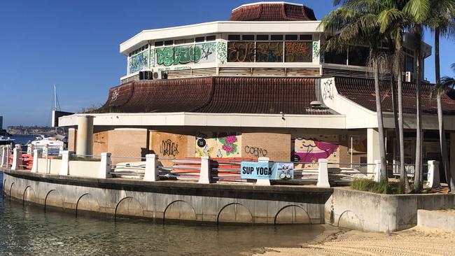 Graffiti vandalism and boarded up windows and doors at the former Sea Life Aquarium building in Manly Cove, on Tuesday. NSW Transport Minister Jo Haylen has said she has called on officials in her department, which owns the site, to “expedite” its demolition. Picture: Jim O’Rourke