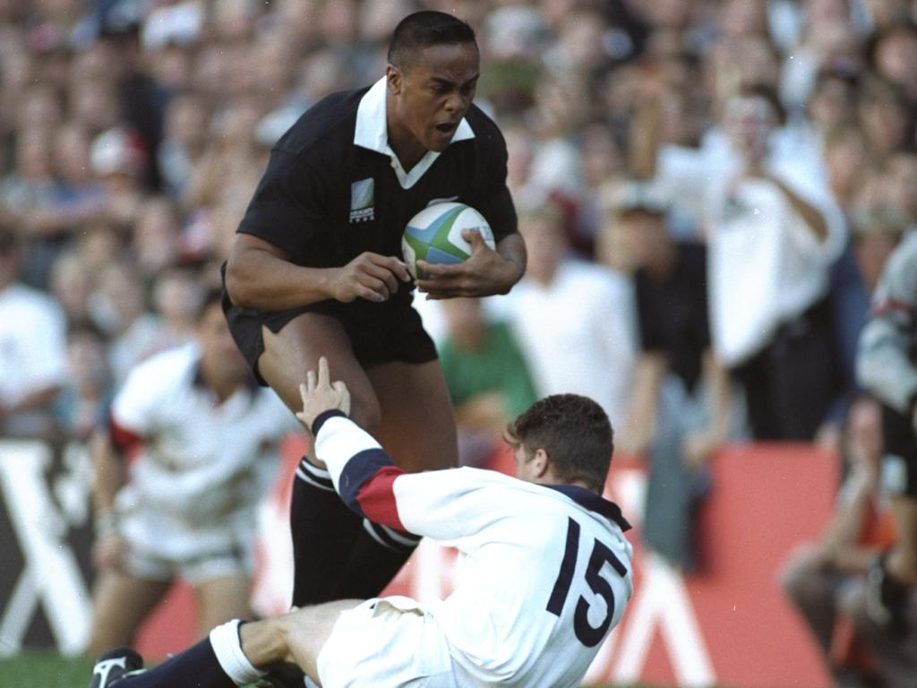 Jonah Lomu charges through the tackle attempt of Mike Catt of England.