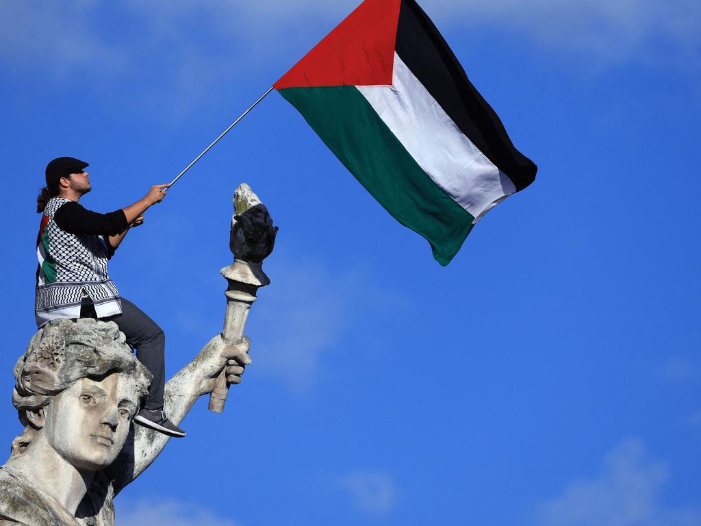 A protester waves a Palestinian flag sitting on the statue "Le Triomphe de la Republique" (The Triumph of the Republic) during a demonstration calling for peace in Gaza, at Place de la Republique in Paris. Picture: AFP