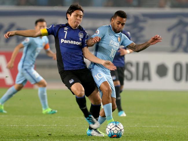 Alex Teixeira (R) fights for the ball with Yasuhito Endo. / AFP PHOTO / STR / CHINA OUT