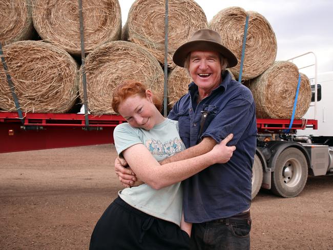 Les Jones and daughter Lillie celebrate the arrival of bales of hay from Victoria. Need for Feed donated the hay and delivered it to save their flock. Picture: Sam Ruttyn