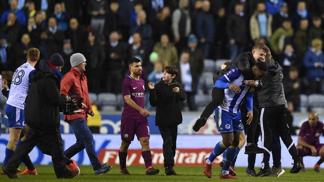 Manchester City's Argentinian striker Sergio Aguero (C) walks as supporters invade the pitch after the English FA Cup fifth round football match between Wigan Athletic and Manchester City at the DW Stadium in Wigan, northwest England, on February 19, 2018. / AFP PHOTO / Oli SCARFF / RESTRICTED TO EDITORIAL USE. No use with unauthorized audio, video, data, fixture lists, club/league logos or 'live' services. Online in-match use limited to 75 images, no video emulation. No use in betting, games or single club/league/player publications.  /