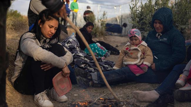 Migrants from Venezuela sit by a makeshift fire to warm up as they wait to enter and seek asylum in El Paso, Texas. President Biden is struggling to blame his predecessor for border chaos after a record number of migrants were stopped in December. Picture: Christian Monterrosa/AFP