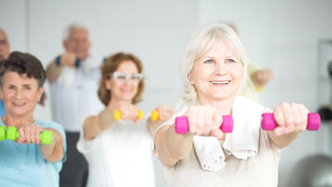 Elderly women holding dumbbells during group exercise class for senior citizens