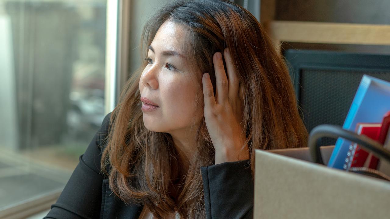 An Asian woman in the office thinking while looking out of the window daytime. Picture: iStock