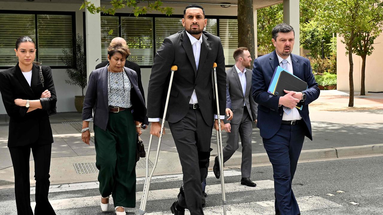 Nick Kyrgios (C) arrives on crutches to the magistrate's court in Canberra on February 3, 2023. (Photo by SAEED KHAN / AFP)