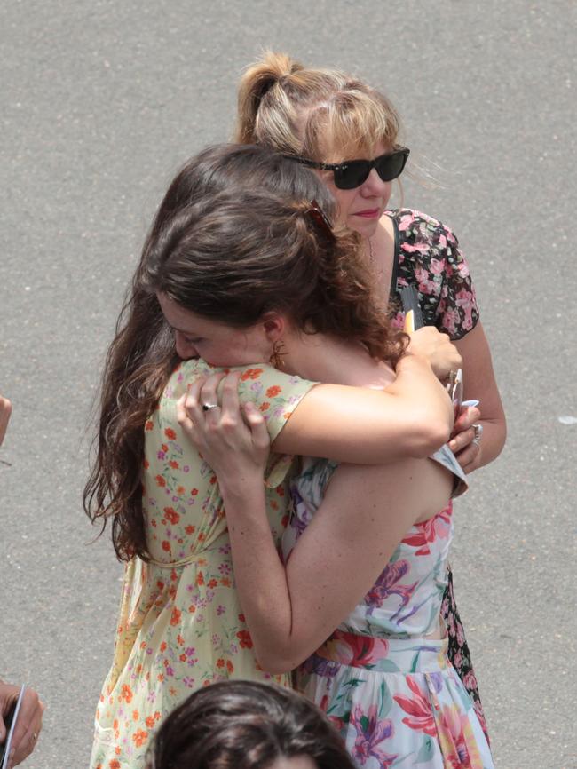 Mourners embrace following the service. Picture: AAP