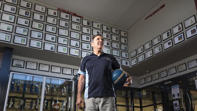 Kevin Goorjian with the school’s trophy cabinet and hall of fame.