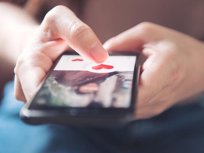 Finger of woman pushing heart icon on screen in mobile smartphone application. Online dating app, valentine's day concept.