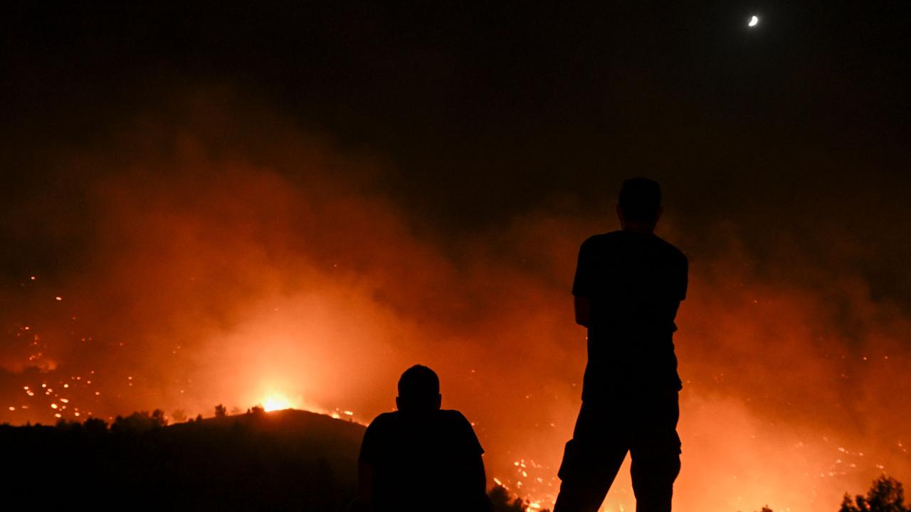 People watch the fires near the village of Malona. (Photo by SPYROS BAKALIS / AFP)