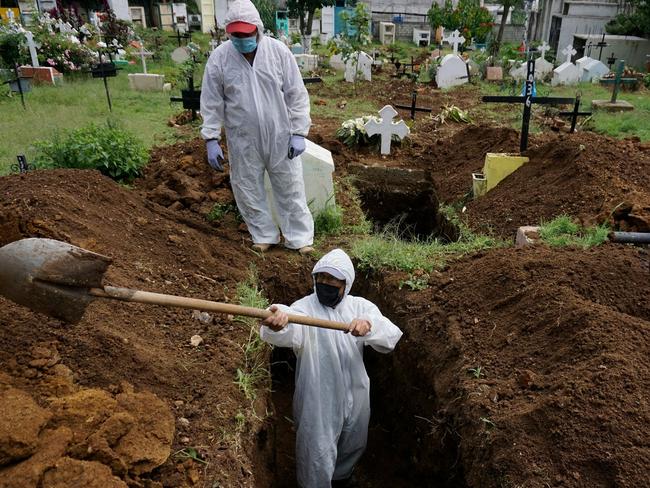 TOPSHOT - A gravedigger wearing a biosafety suit digs a grave to bury the coffin of a COVID-19 victim at the Mixco municipal cemetery, in Mixco, 20 km west of Guatemala City, on August 6, 2020. - Guatemala surpassed 2.119 deaths by COVID-19 and has more than 54.339 contagions, at a time when the Central American country has been gradually reopening restricted economic activities since March, the government reported. (Photo by Johan ORDONEZ / AFP)