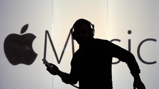 A man dances to music being streamed on his Apple Inc. iPhone 6s whilst framed against a wall bearing the Apple music symbol in this arranged photograph in London, U.K., on Wednesday, Dec. 23, 2015. Beatles songs will now be available around the world on nine streaming services including Apple, Spotify, Deezer and Google Play, the bands record company, Vivendi SAs Universal Music Group, said Wednesday in a statement. Photographer: Chris Ratcliffe/Bloomberg