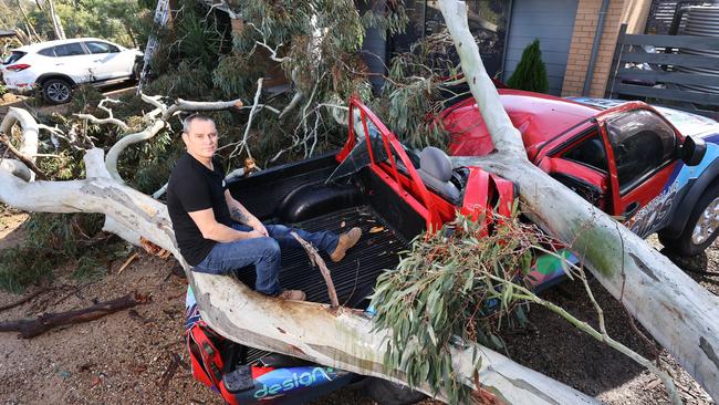 CFA volunteer Simon Hinneberg just escaped death and had his work ute crushed in the storms. The tree is still on the ute, as well as his house, in Kyneton, Victoria. Picture: Alex Coppel.