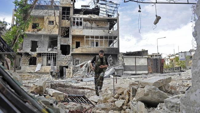 A Syrian rebel runs across a heavily damaged street to dodge sniper fire during clashes with government forces in Aleppo. Picture: AFP