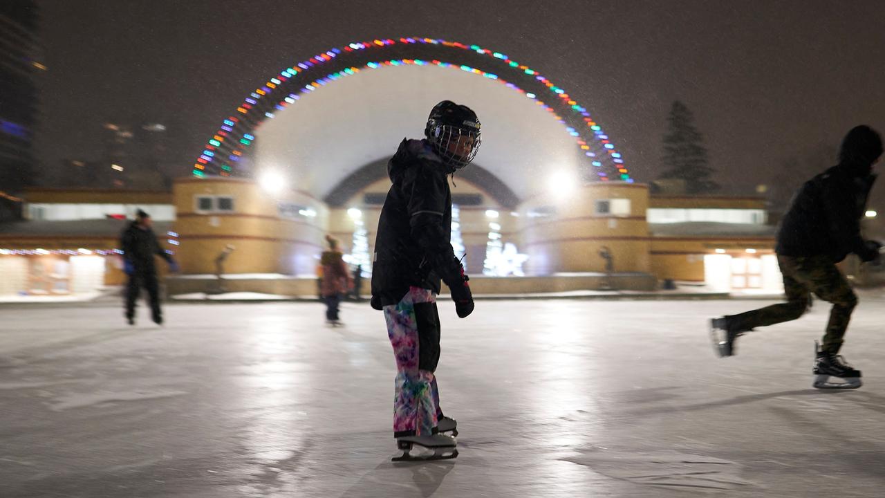 People skate on an outdoor rink at Victoria Park during a large winter storm in London, Ontario, Canada. (Photo by Geoff Robins / AFP)